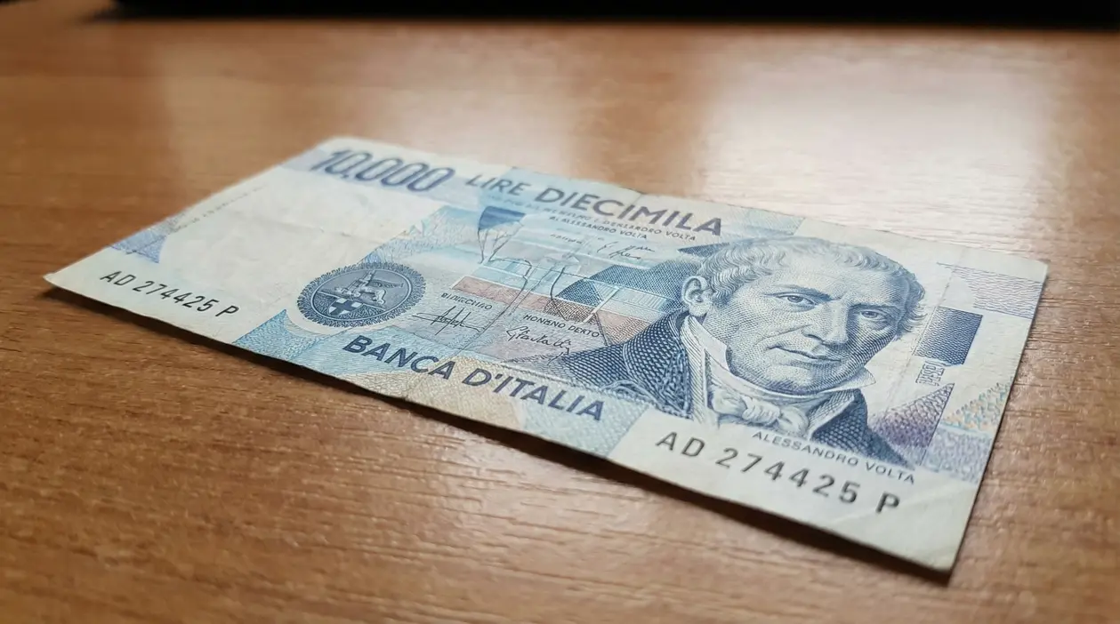Banconota da 10.000 lire con ritratto di Alessandro Volta su un tavolo di legno.