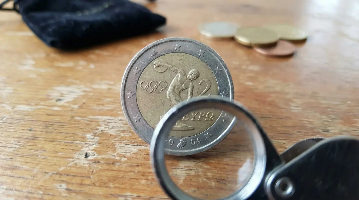 Moneta da 2 euro greca con simbolo del gufo osservata con lente d'ingrandimento