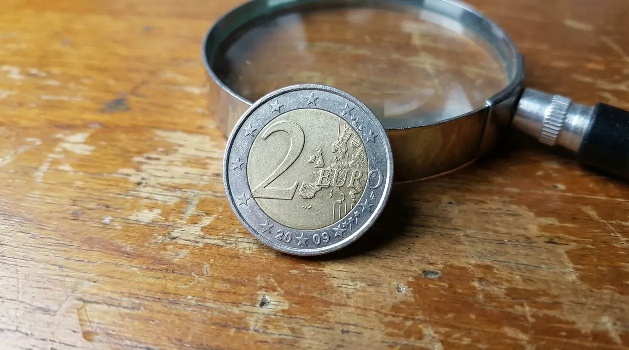 Moneta da 2 euro del 2009 appoggiata su un tavolo con lente d'ingrandimento