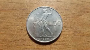 Moneta da 50 lire del 1990 con figura maschile e incudine su sfondo in legno
