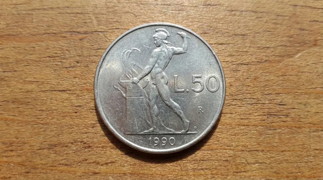 Moneta da 50 lire del 1990 con figura maschile e incudine su sfondo in legno