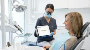 Una dentista mostra un tablet con un calendario a una paziente seduta sulla poltrona odontoiatrica