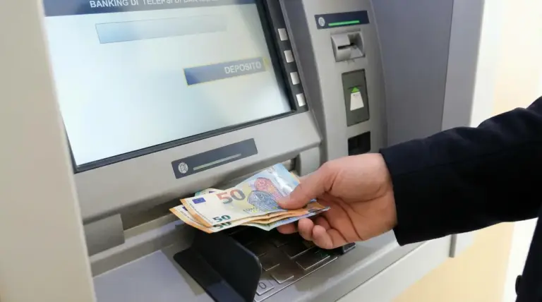 Persona inserisce banconote in uno sportello automatico per effettuare un deposito