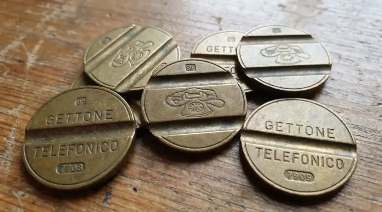 Vecchi gettoni telefonici SIP in metallo su una superficie in legno