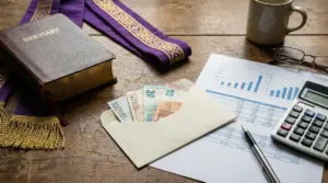 Busta con banconote in euro, libro liturgico e documenti finanziari su un tavolo